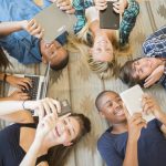 Teenagers laying on floor using technology